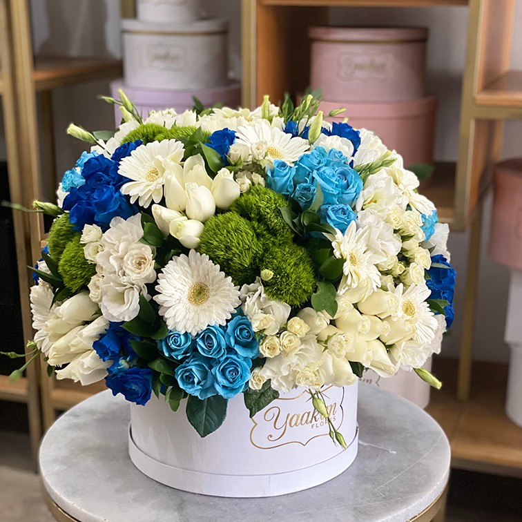 Caja circular blanca con 100 rosas blancas y azules y follajes finos