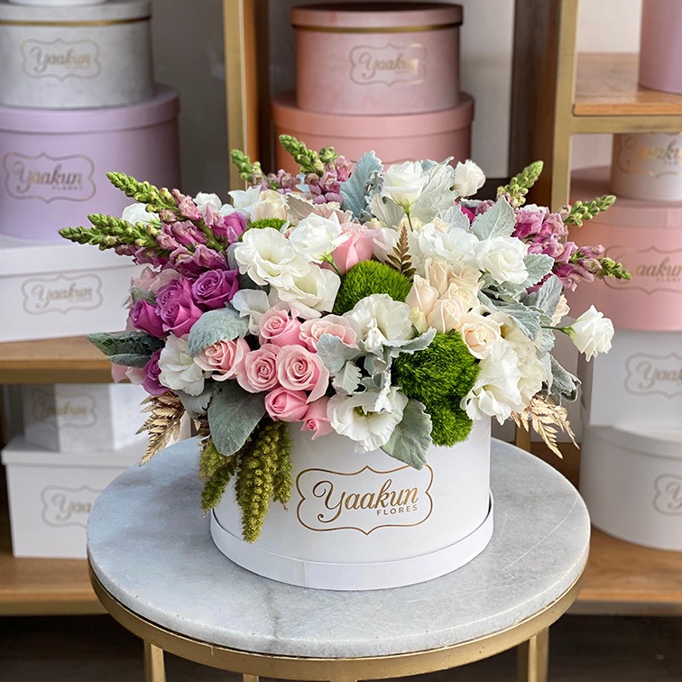 Caja circular blanca con 75 rosas rosas y lilas, follajes y flores finas toques dorados