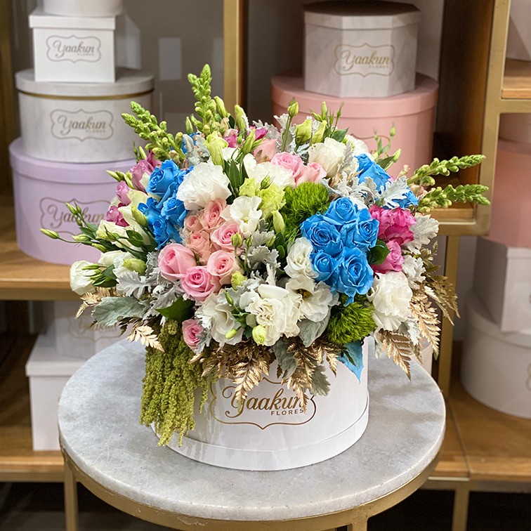 Caja circular blanca con 75 rosas, rositas, blancas y azules y follajes finos toques de leader dorado
