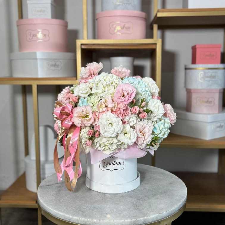 Caja circular blanca con hortensias, rosas, blancas azul y lisianthus