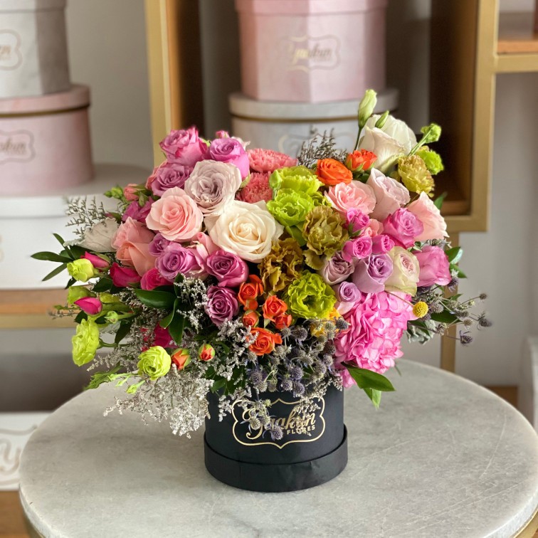 Caja circular negra con 50 rosas en tonos pastel, lisianthus verde, baby rose toques de caspia y eringio