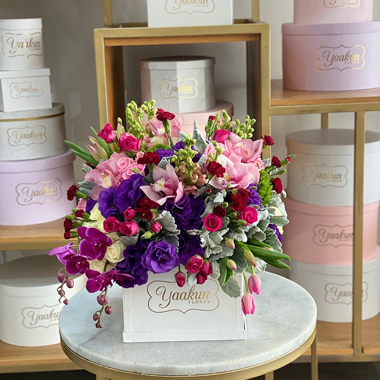 Caja cuadrada blanca con 100 rosas en tonos pastel con tulipanes, perritos y orquídeas