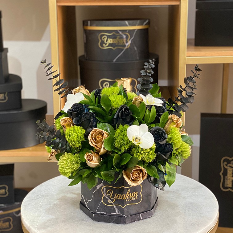 Caja octagonal negra, con 24 rosas negras y doradas toque de dólar negra,green y orquídeas blancas phalenosis
