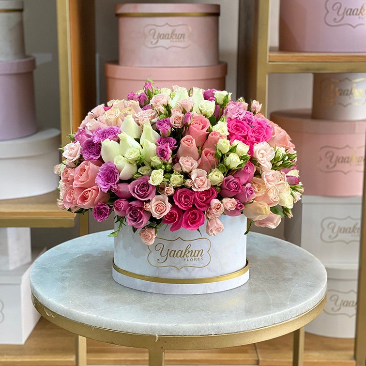 Caja ovalada blanca con 150 rosas en tonos pastel y toques de baby rose
