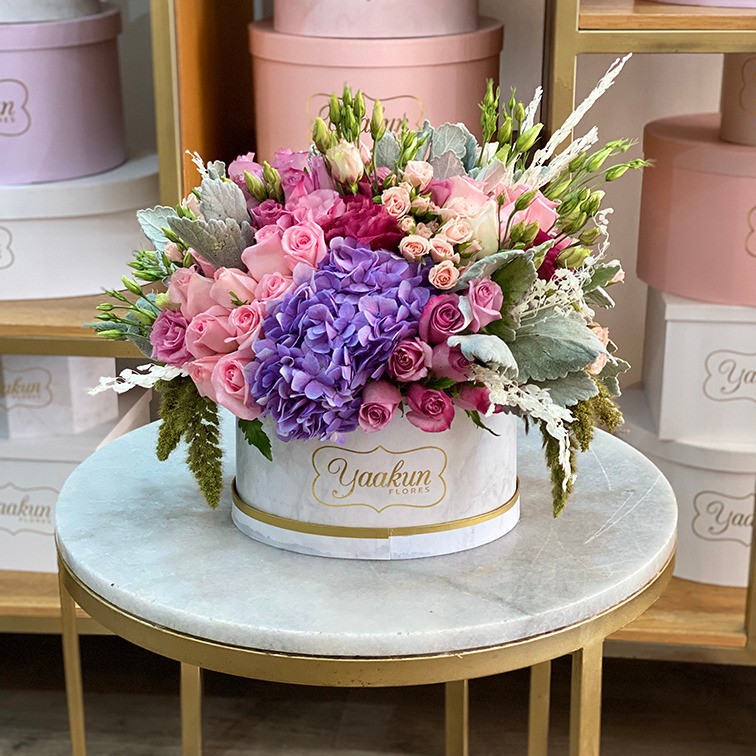 Caja ovalada blanca con 50 rosas con tonos rosa & lila, hortensias y follajes