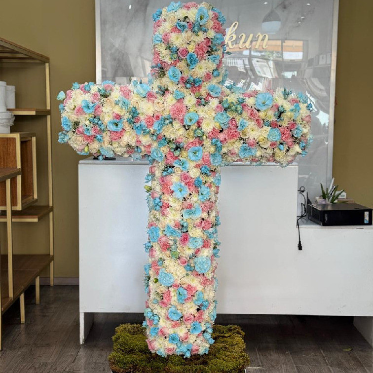 Escultura en forma de cruz con 300 rosas en tonos blancos, rosas y azules