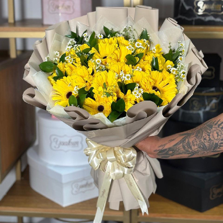Ramo de 24 gerberas amarillas con ruscus y manzanilla en papel coreano